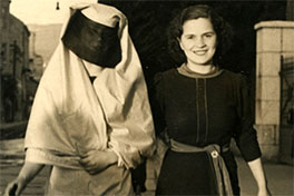 A woman wearing a dark urban dress is walking down the street with a Muslim woman wearing a veiled robe and a black veil covering her face.